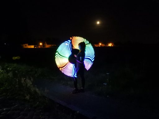 Silhouette einer Person mit buntem Lichtspiel, Hintergrund mit Mond und Straßenlichtern.